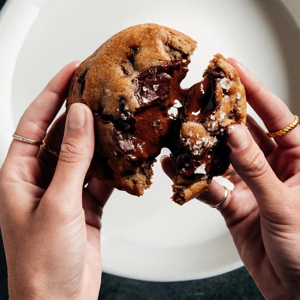 hands breaking chocolate chip cookie